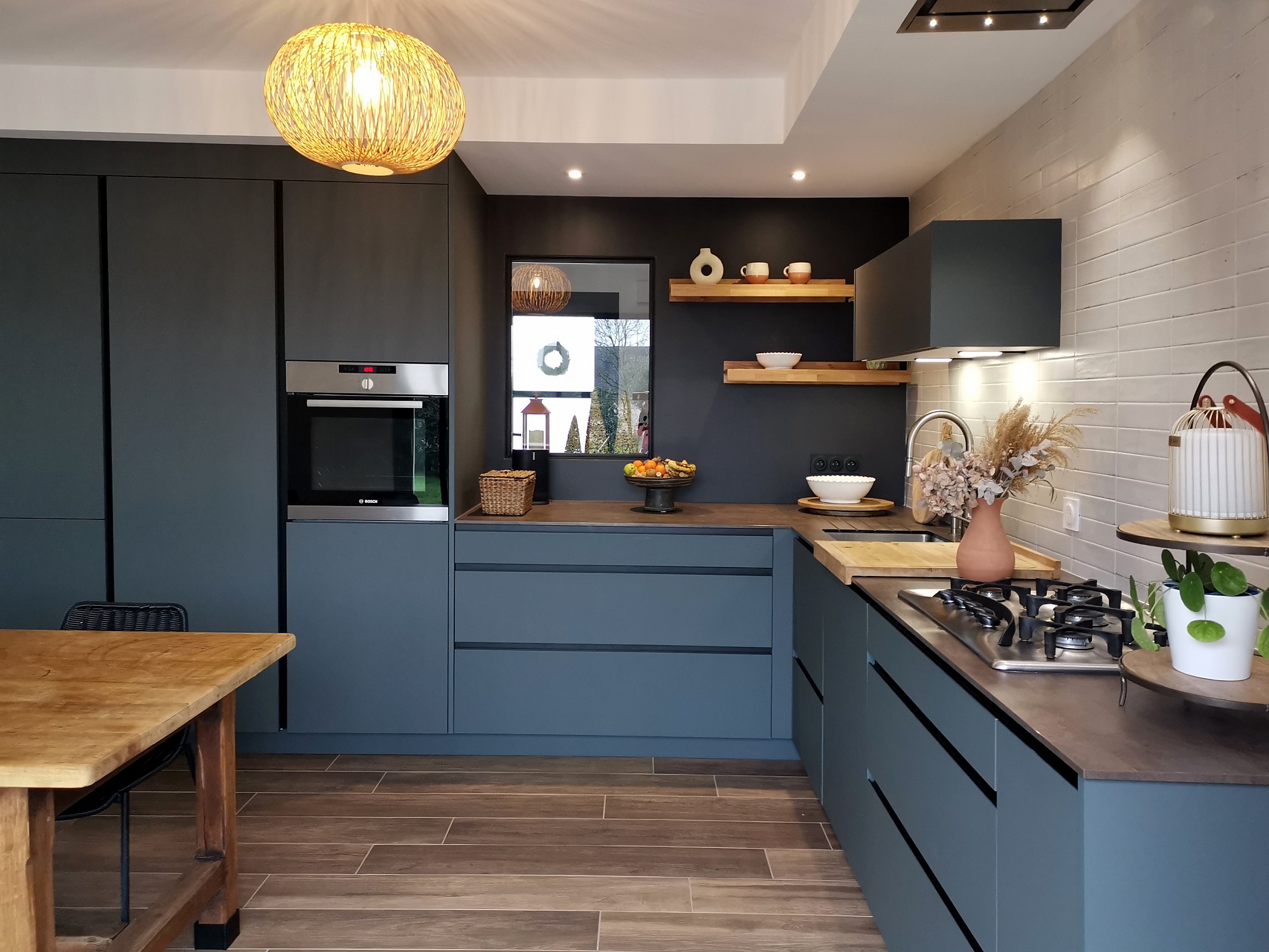 Cocina moderna en forma de U con muebles azul grisáceo, encimera de madera oscura y paredes con azulejo blanco