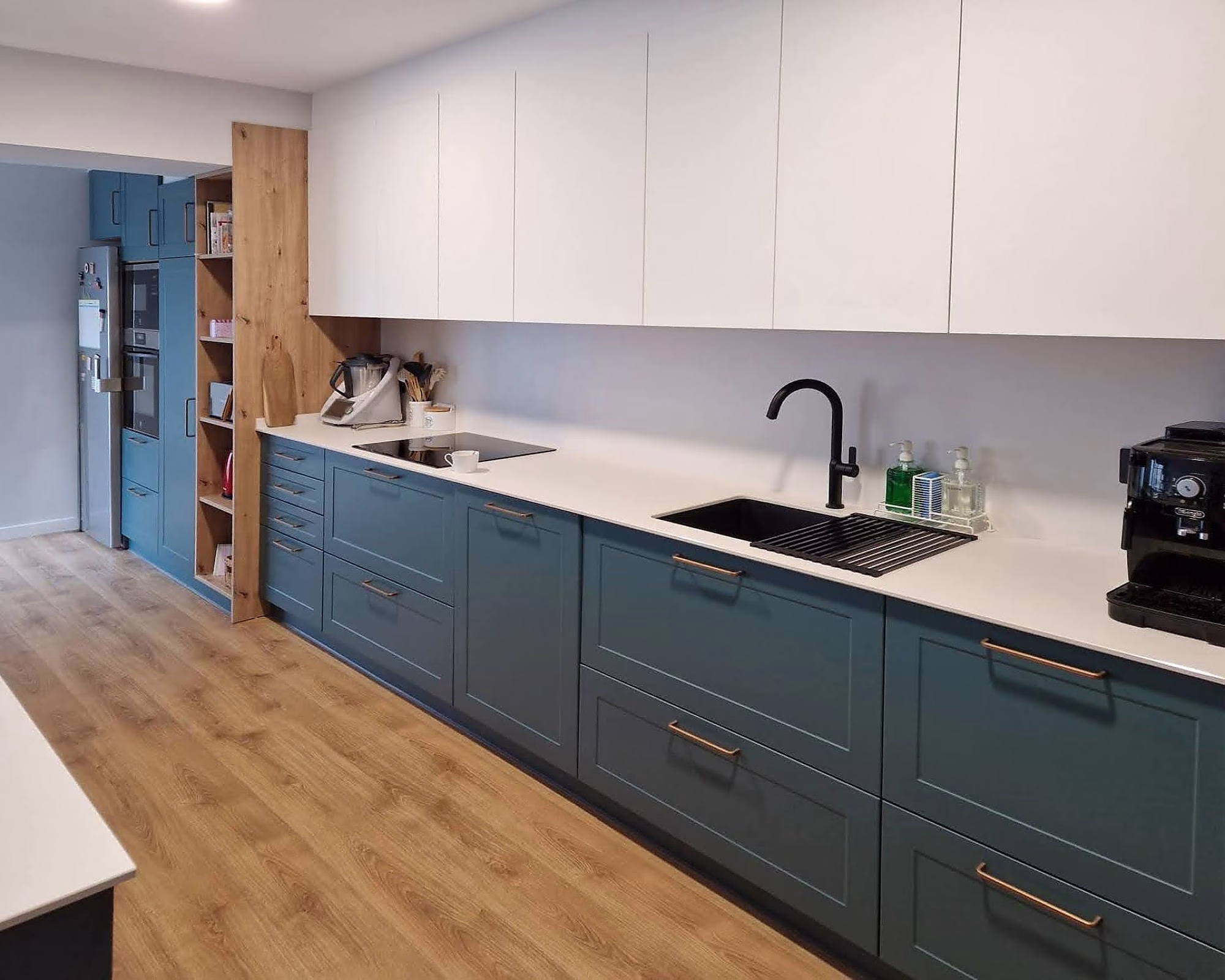 Cocina moderna azul y blanca con encimera clara y grifo negro