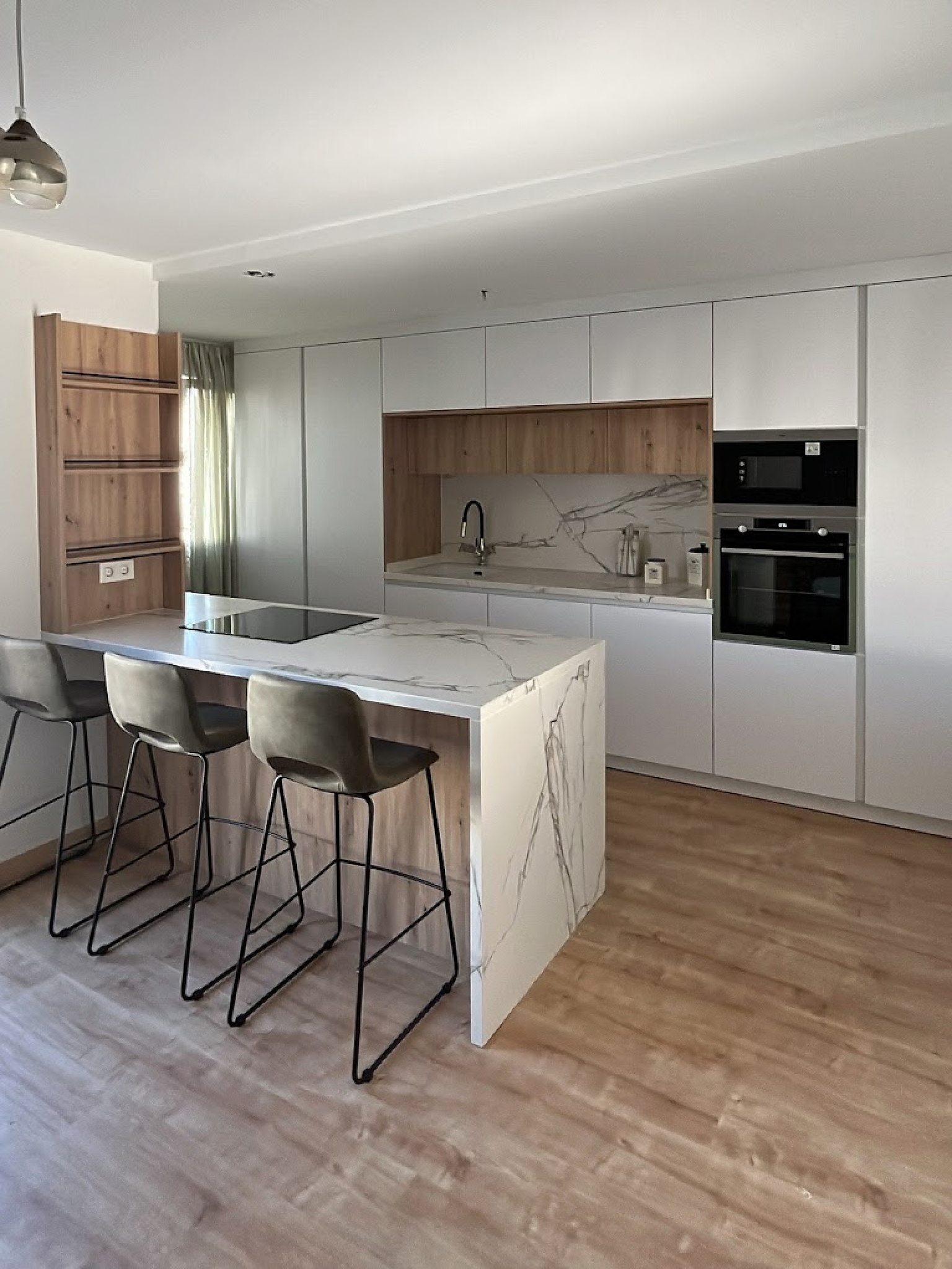 Cocina moderna con isla de mármol y muebles blancos con detalles en madera