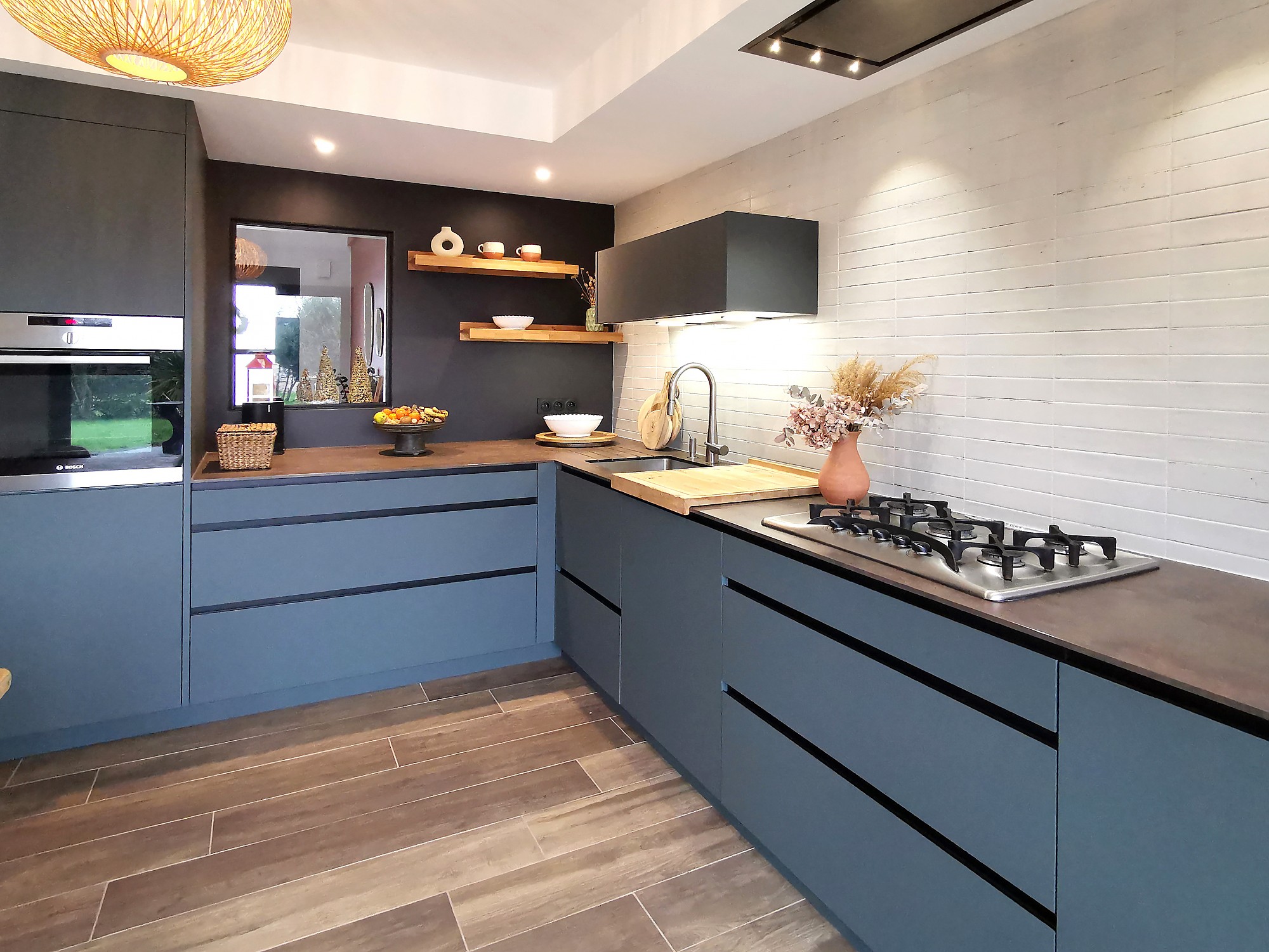 Cocina moderna con muebles azul grisáceo, encimera de madera oscura y paredes con azulejo blanco