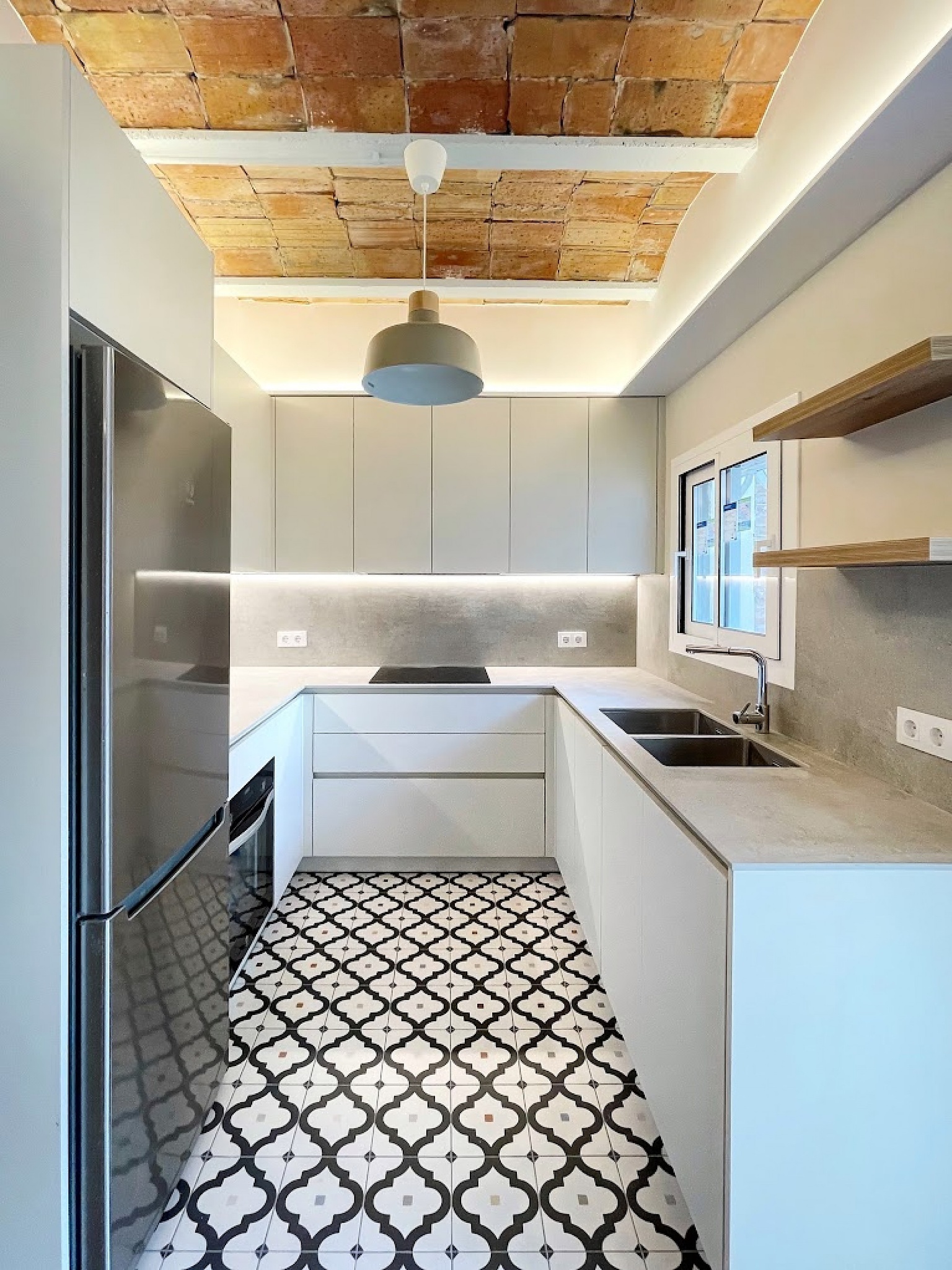 Cocina en forma de L con techo de bóveda catalana y suelo hidráulico blanco y negro.