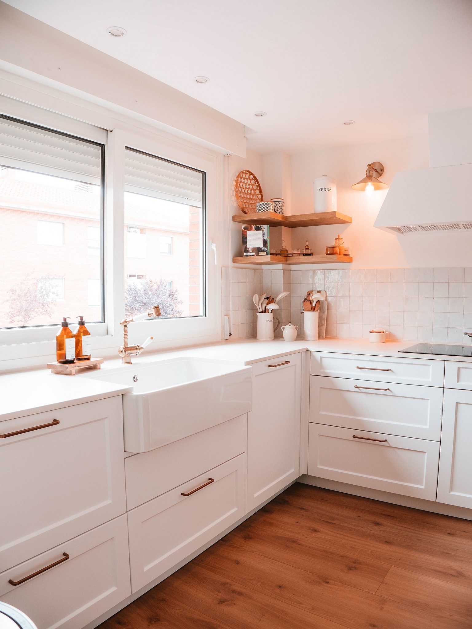 Cocina blanca con fregadero tipo granja y detalles en madera.