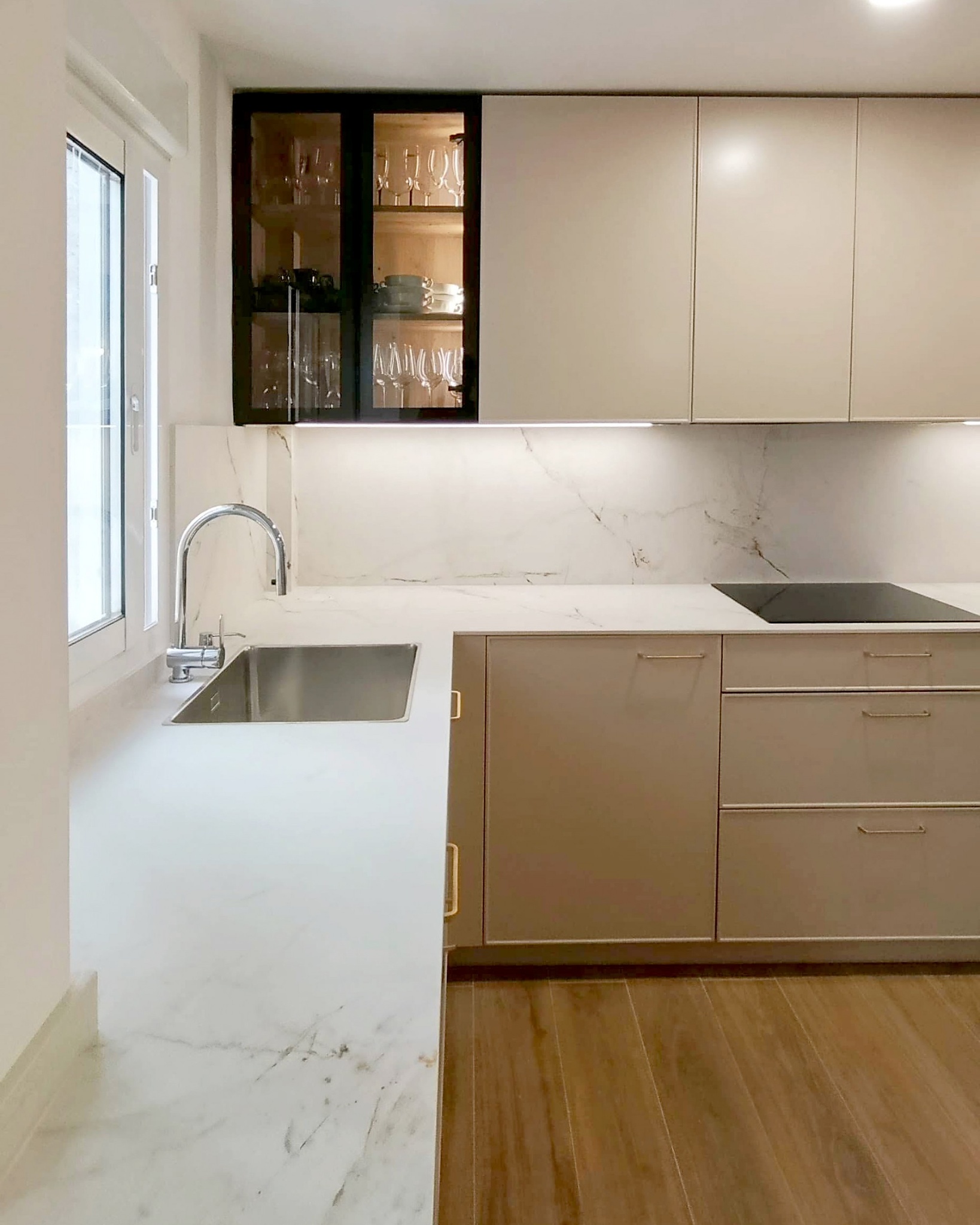 Cocina moderna beige con encimera de mármol blanco y vitrina negra